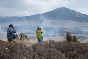 草千里野焼き撮影する写真愛好家